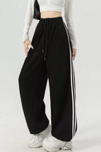 Black wide leg track pants with two vertical white stripes for a stylish wide leg silhouette striped pants design