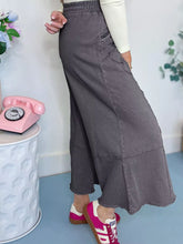 A dark gray high waisted wide leg denim skirt with relaxed fit and visible stitching in flower patch mineral washed terry knit