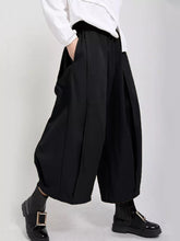 Black wide leg pleated trousers with relaxed flowing silhouette and subtle pleats for elegant wear