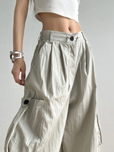 Light beige drawstring wide leg cargo pants with pleated detailing and black button accents for versatile wear