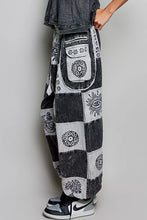 Black and white patchwork denim jogger pants with embroidered floral eye and tree-of-life motifs in soft cotton fabric