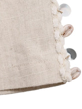Beige linen drawstring wide leg pants featuring a decorative edge with white pom-poms and natural metallic seashells