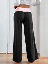 Black wide leg pants with a pink contrast waistband highlighting the contrast waistband wide leg design