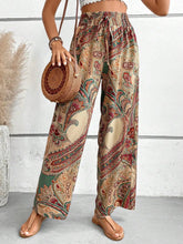 Printed wide leg pants featuring beige red and green paisley pattern with wide leg and drawstring waistband