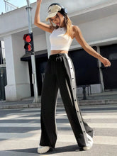 Black two-tone snap wide leg pants featuring a white vertical stripe and silver buttons down the side