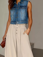 Blue denim sleeveless vest with frayed edges and silver buttons paired with high waist wide leg pants