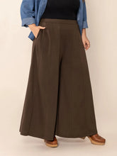 Plus size wide leg brown trousers with high waist, subtle pleats, smooth flowing fabric, and pockets
