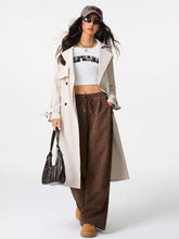 Black leather shoulder bag with structured shape and multiple zippers paired with corduroy wide leg pants