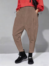 Loose fit harem pants in beige herringbone texture with tapered jogger style, side pockets, and drawstring cuffs