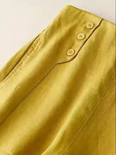 Mustard-yellow satin wide-leg pants with three matching button closures along the waistband