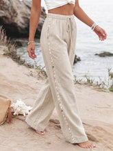 Beige linen drawstring wide leg pants with decorative shell trim along the side seam for a stylish look