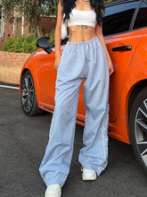 Light blue wide leg pants with white side stripes and drawstring waist designed for athletic wear