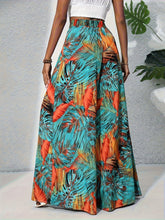 A vibrant tropical print wide leg pants in turquoise orange and brown tones featuring a tropical print design