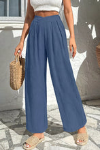 Blue solid color textured wide-leg trousers with pleated design and crossed waist in soft flowing fabric