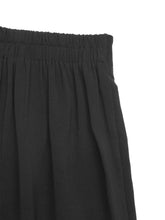 Black pleated skirt with elastic waistband shown alongside floral lace hem wide leg pants in black fabric