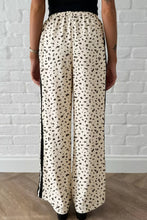 Cream-colored loose drawstring pants with black leopard print and contrasting black side stripe detail