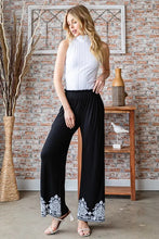 Black wide-leg Heimish full size solid damask casual pants with intricate white embroidered patterns on cuffs