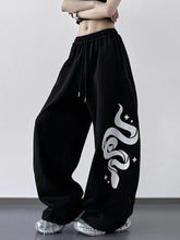 Wide leg drawstring black sweatpants featuring a bold white snake graphic with star accents along the side