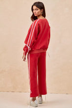Red oversized fleece sweatshirt with white vertical stripes and lined bow details drawstring ties at cuffs and hem