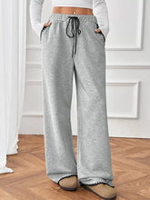 Wide-leg pants in gray heathered fabric with black drawstring and scalloped trim, machine wash care instructions