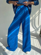 Vibrant cobalt blue wide leg pleated pants with a satin finish offering elegant style and care instructions included