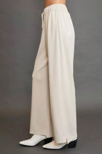 Cream-colored umgee wide leg pants with elastic drawstring waistband and subtle side slit for comfortable wear