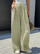 Striped wide leg pants in olive green and dark brown with vertical stripes made of lightweight fabric