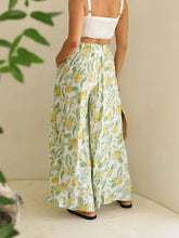 White wide leg trousers with green and yellow tropical pineapple print featuring a drawstring paperbag waist