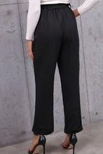 Black high-waisted belted paperbag waist pants with elastic waistband and modern wide-leg cut