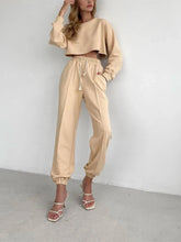 Beige cropped sweatshirt with long sleeves paired with casual drawstring jogger pants for a relaxed fit look