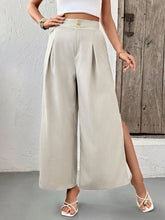 Beige slit wide leg pleated pants featuring high waist and front slit detail in a wide leg pleated design
