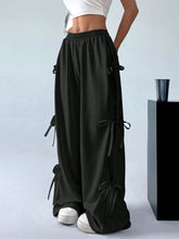 Black satin cargo wide leg pants featuring multiple side tie details along the legs for a stylish look
