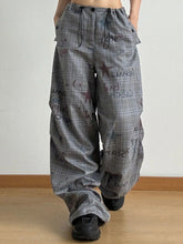 Gray plaid drawstring plaid wide leg cargo pants with loose fit black waist drawstrings and dark cosmic graphics