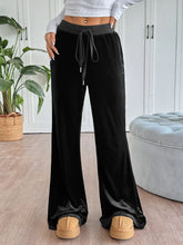 Black velvet wide-leg drawstring pants with a contrasting gray drawstring waistband and care instructions