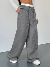 Striped wide leg drawstring pants in black and white vertical stripes with elastic waistband and drawstring closure