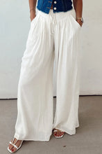 White flowy wide leg pants with drawstring waist and side pockets made from lightweight fabric for comfortable wear