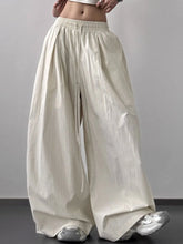 Cream-colored striped wide leg drawstring pants with vertically ribbed texture and elastic waistband