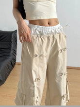 Beige cargo wide leg pants with satin-lined elastic waistband and decorative fabric ties on the sides