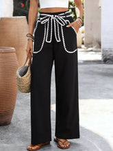 Black wide leg pants with white crochet trim and tie waist bow featuring crochet trim tie waist detail