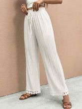 White pleated wide leg pants featuring delicate lace trim wide hem for elegant and stylish wear