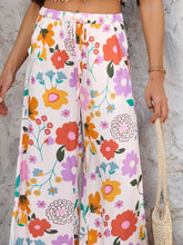 Devine drawstring pants featuring wide-leg floral print with orange pink purple and yellow blossoms on cream fabric with care instructions