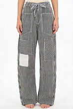 Striped wide-leg pants feature black and white vertical stripes with patchwork pockets and a white square panel detail