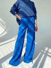 Bright blue wide leg pleated pants with smooth flowing fabric and subtle sheen including care instructions