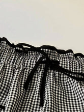 Black and white gingham pants with ruffled waistband and black drawstrings in wide-leg pants style