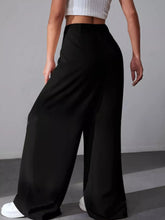Black high-waisted wide leg pleated pants in smooth flowing fabric ideal for elegant and comfortable wear