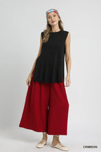 A woman wearing umgee elastic waist wide leg pants in crimson paired with a sleeveless black top