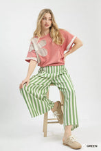 Pink short-sleeved top with white lace butterfly appliqué and ruffled cuffs paired with umgee vertical stripe wide leg pants