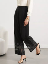 Black high-waisted wide-leg trousers featuring a floral lace hem with lace hem wide design detailing