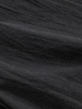 Black textured fabric of elastic waist pants with pockets featuring a subtle woven pattern and comfortable elastic waist