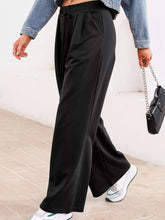 Black wide-leg sweatpants with tied elastic high waist and subtle pleats for comfortable stylish wear